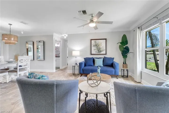 Living room featuring crown molding, ceiling fan, and light wood finished floors