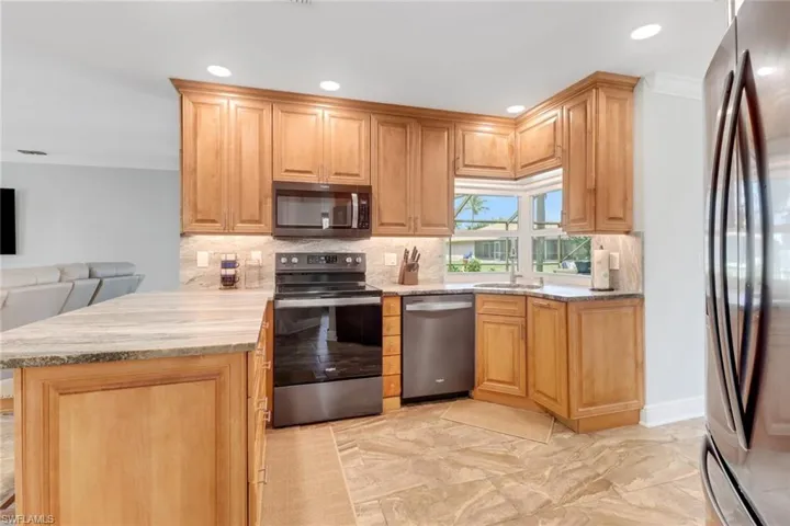 Kitchen with crown molding, a peninsula, stainless steel appliances, backsplash, and recessed lighting