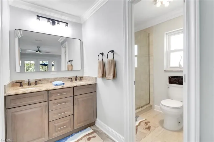 Bathroom featuring double vanity, a stall shower, and crown molding