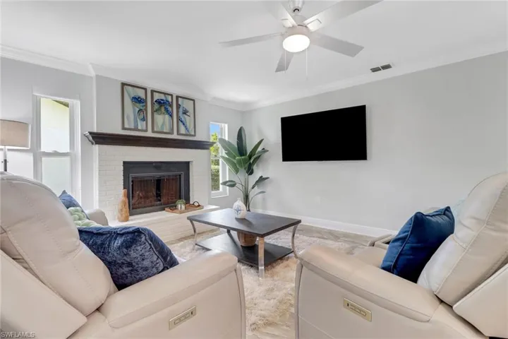 Living room featuring crown molding, a brick fireplace, and a ceiling fan