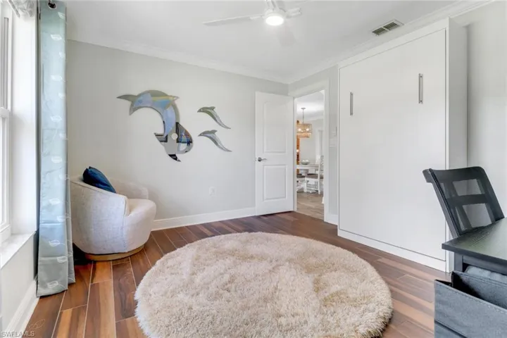 Sitting room with crown molding, dark wood-type flooring, and ceiling fan