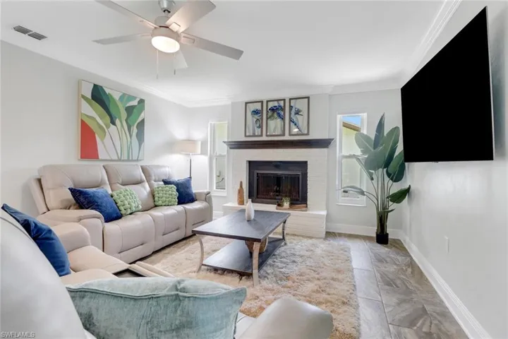 Living room featuring crown molding, ceiling fan, and a fireplace