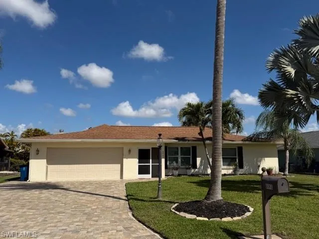 Ranch-style house with an attached garage, stucco siding, driveway, and a front yard