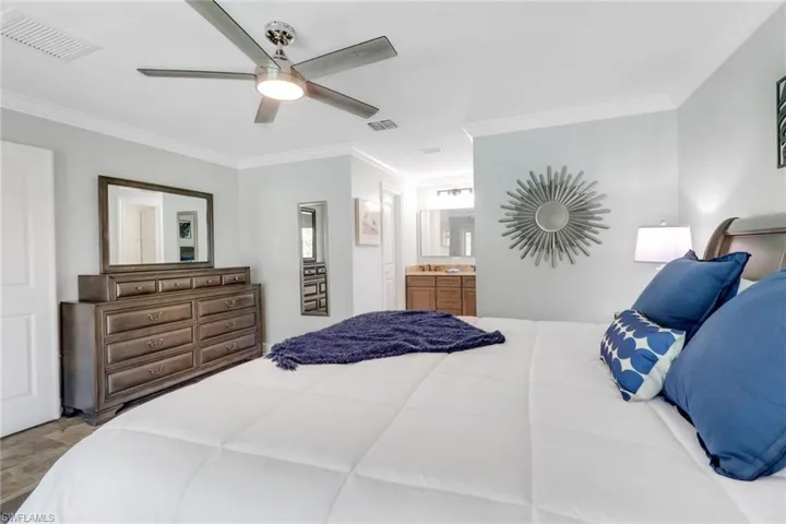 Bedroom featuring ornamental molding, ceiling fan, and ensuite bath