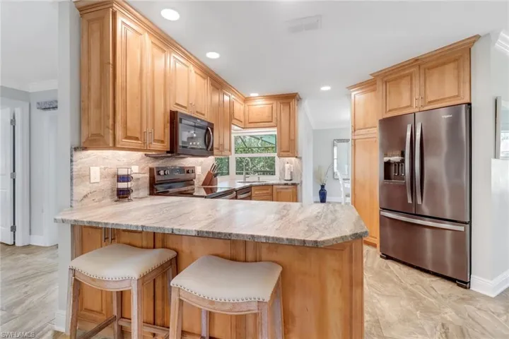 Kitchen with a peninsula, stainless steel appliances, a breakfast bar, tasteful backsplash, and crown molding