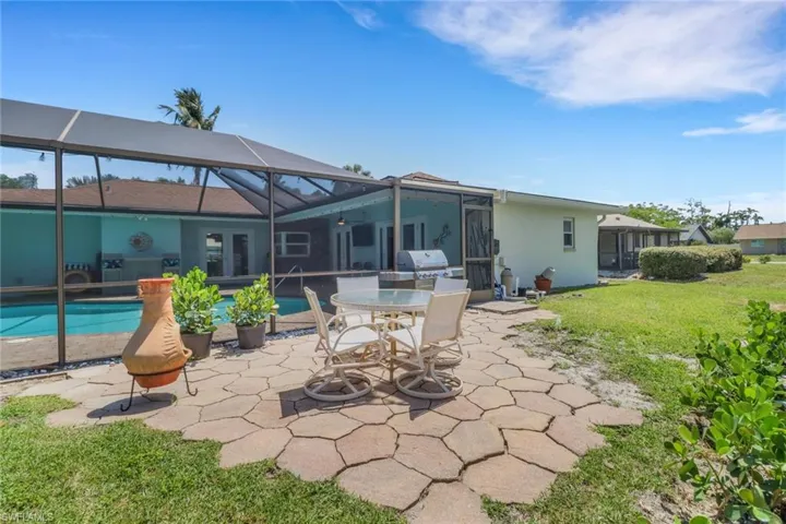 Back of house featuring a patio area, a sunroom, a lanai, a yard, and outdoor dining area