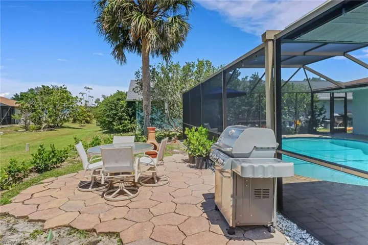 View of patio featuring a sunroom, a lanai, an outdoor pool, outdoor dining area, and grilling area