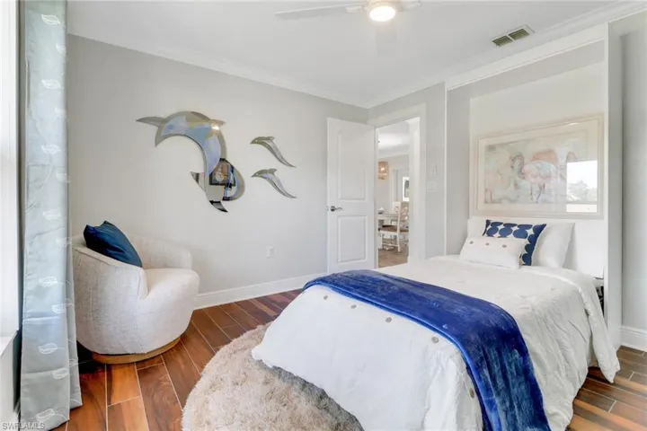 Bedroom featuring wood finish floors, crown molding, and ceiling fan