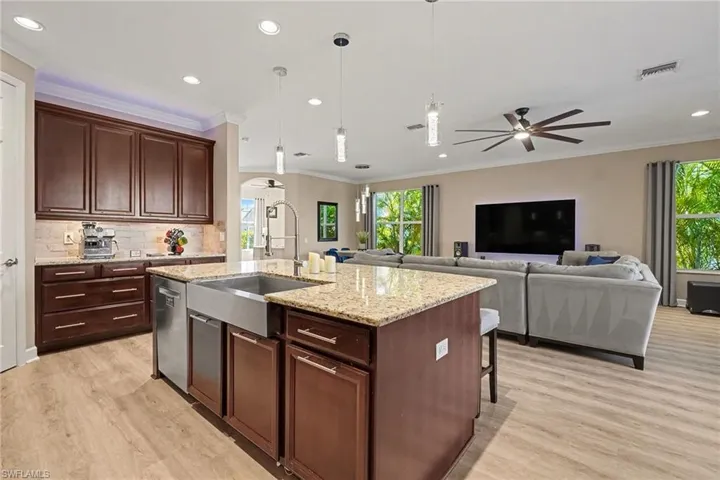 Kitchen with pendant lighting, dark brown cabinets, an island with sink, a kitchen bar, and decorative backsplash