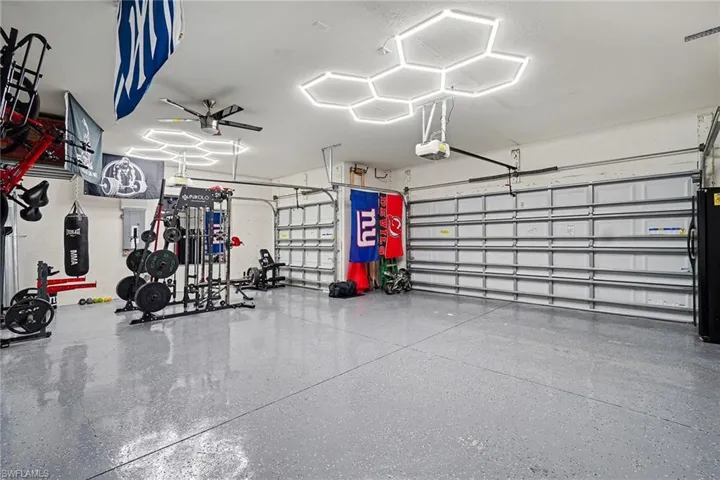 Garage featuring electric panel, freestanding refrigerator, and a garage door opener
