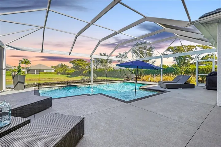 Screened lanai featuring a swimming pool, concrete patio, and water frontage