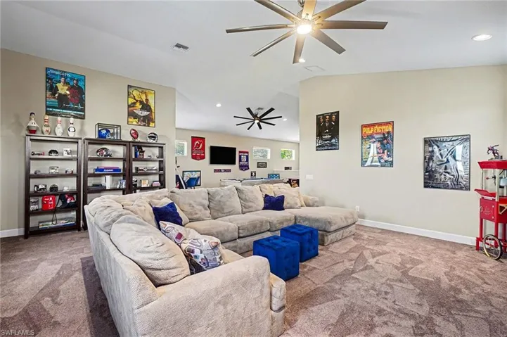 Carpeted living area with ceiling fan, recessed lighting, and vaulted ceiling