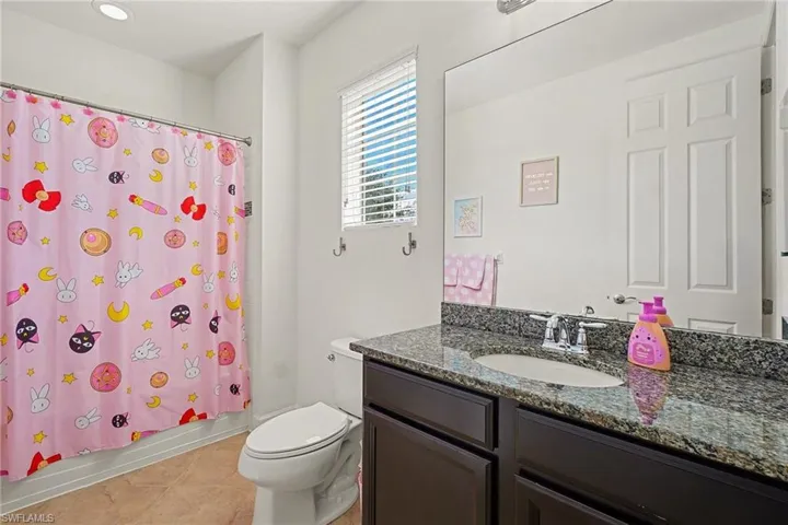 Bathroom with vanity, shower / tub combo with curtain, and light tile patterned floors