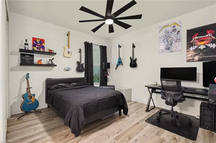 Bedroom featuring a desk, light wood-style floors, and ceiling fan