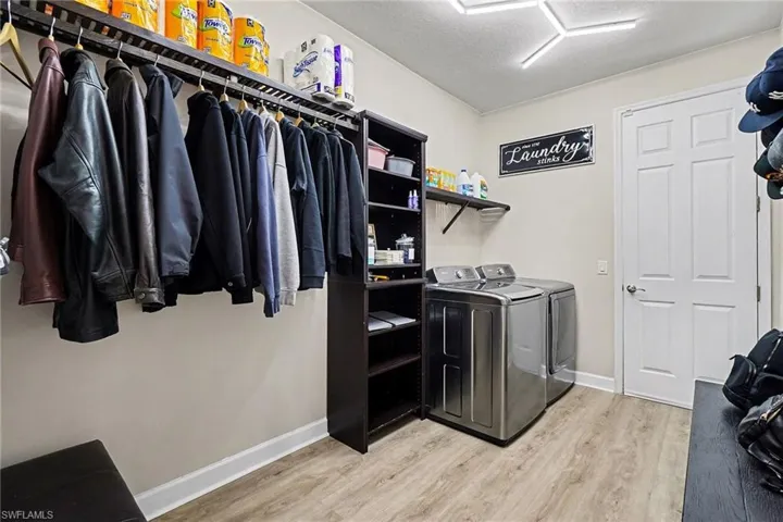 Laundry room featuring light wood-style floors, washing machine and dryer, and a textured ceiling