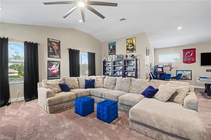 Carpeted living area featuring healthy amount of natural light, vaulted ceiling, recessed lighting, and a ceiling fan