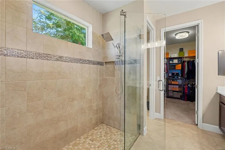 Full bath with vanity, a spacious closet, a shower stall, and light tile patterned flooring