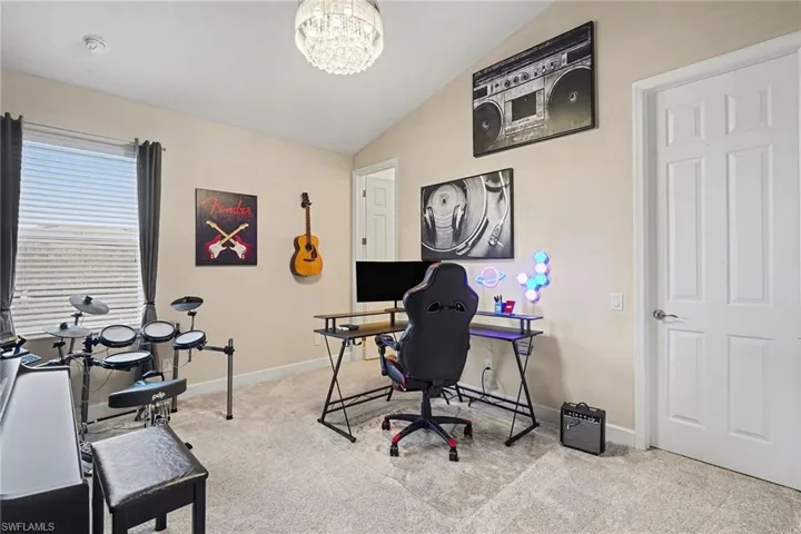 Office space featuring lofted ceiling, light carpet, and a chandelier