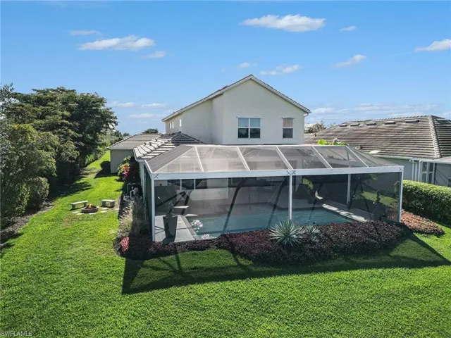 Back of property featuring a lanai, an outdoor pool, stucco siding, a lawn, and a sunroom