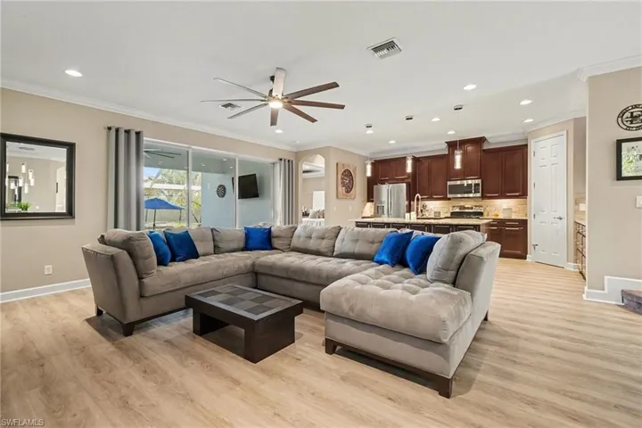 Living area with light wood-style floors, a ceiling fan, ornamental molding, and recessed lighting