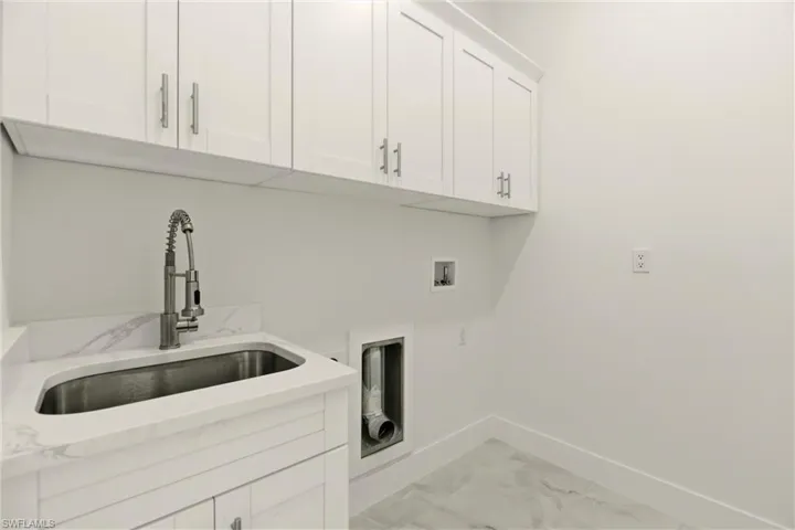Laundry room featuring light marble finish flooring, cabinet space, and washer hookup