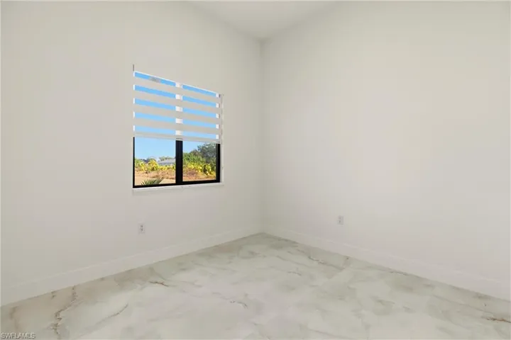Spare room featuring baseboards and light marble finish floors
