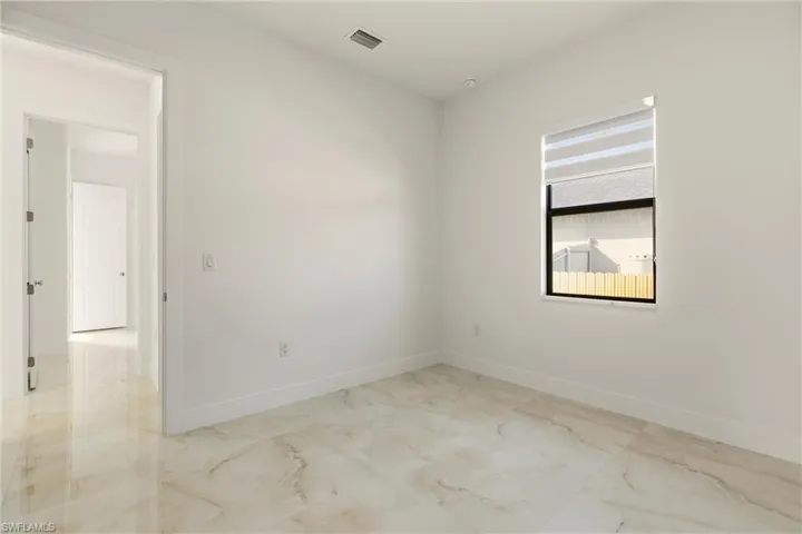 Unfurnished room featuring light marble finish flooring and baseboards