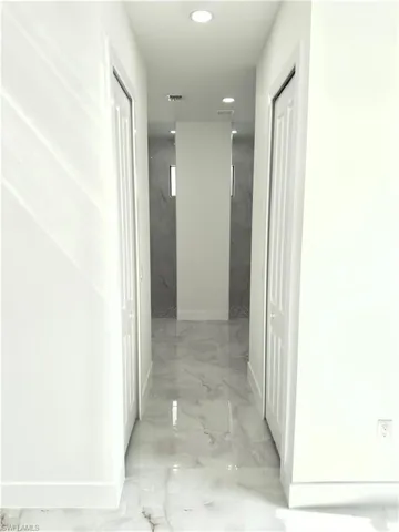 Hall featuring light marble finish floors and recessed lighting