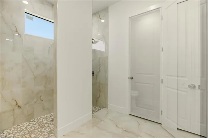 Bathroom featuring a marble finish shower and marble tiled floors