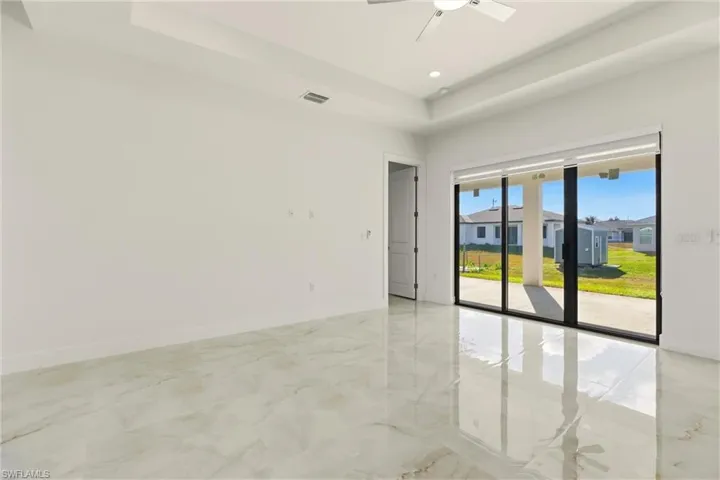 Spare room with light marble finish flooring, a tray ceiling, ceiling fan, recessed lighting, and a residential view