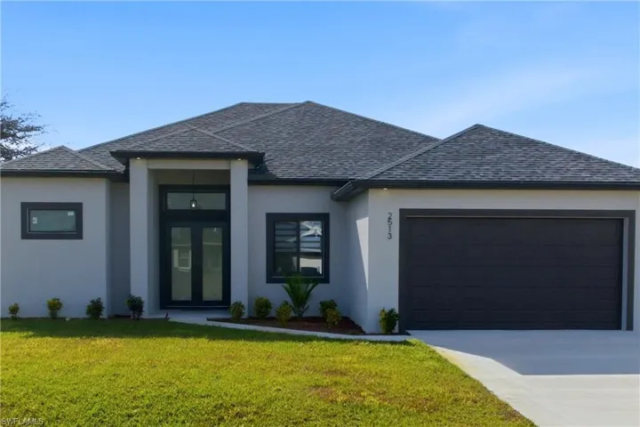 View of front of property with a front yard, stucco siding, driveway, and an attached garage