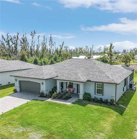 Ranch-style home with stucco siding, a front yard, driveway, and an attached garage