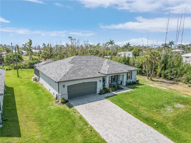 Ranch-style house featuring stucco siding, a front yard, driveway, a shingled roof, and a garage