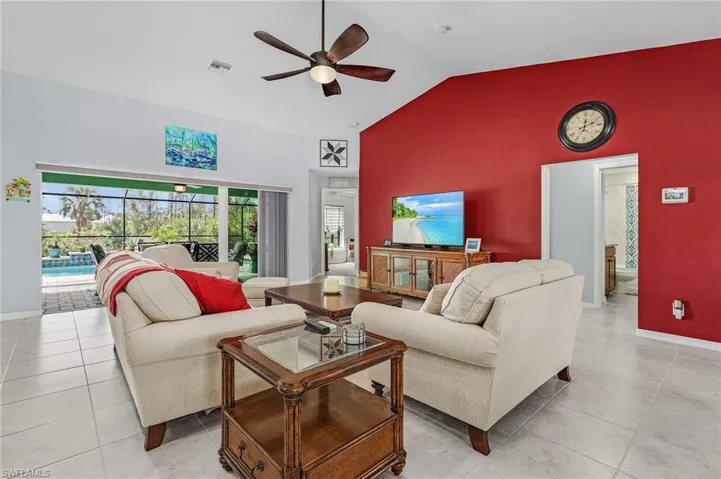 Living area with a high ceiling, a ceiling fan, and light tile flooring