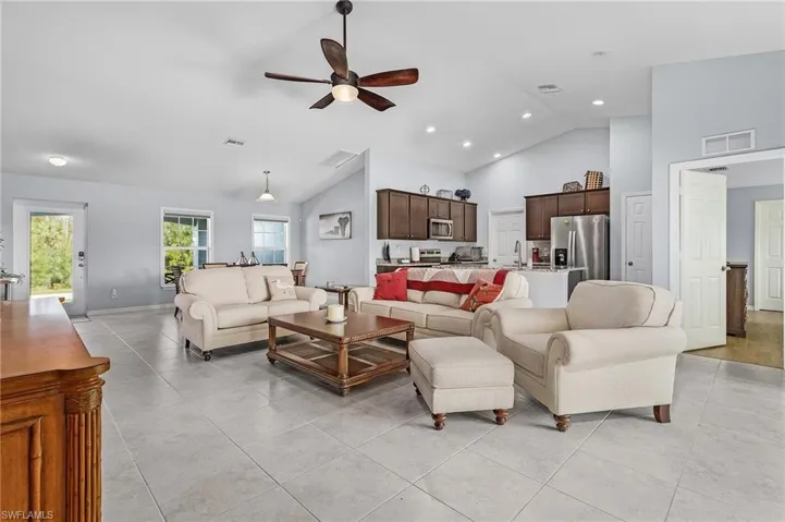 Living area featuring ceiling fan, vaulted ceiling, light tile flooring, and recessed lighting