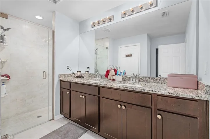 Full bath with double vanity, a stall shower, and recessed lighting