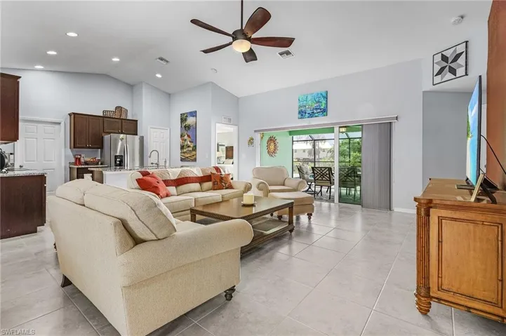 Living area featuring lofted ceiling, a ceiling fan, light tile flooring, and recessed lighting