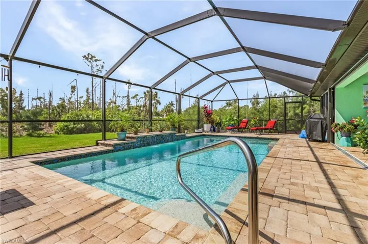 Outdoor screened pool with a patio area, grilling area, and a lawn