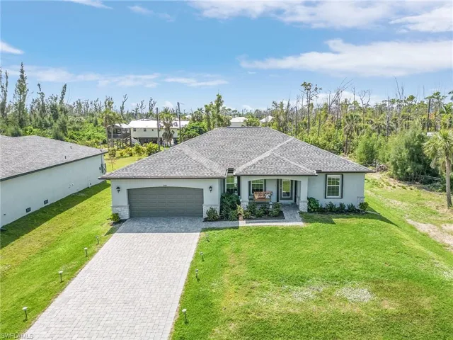 Ranch-style home featuring stucco siding, decorative driveway, a garage, and a front yard