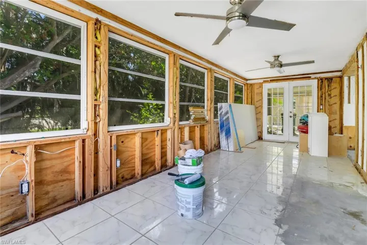 Unfurnished sunroom featuring ceiling fan and french doors