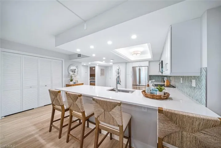 Kitchen featuring light wood-type flooring, kitchen peninsula, high end refrigerator, a breakfast bar, and sink