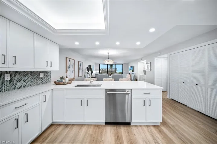 Kitchen with white cabinets, kitchen peninsula, sink, and dishwasher