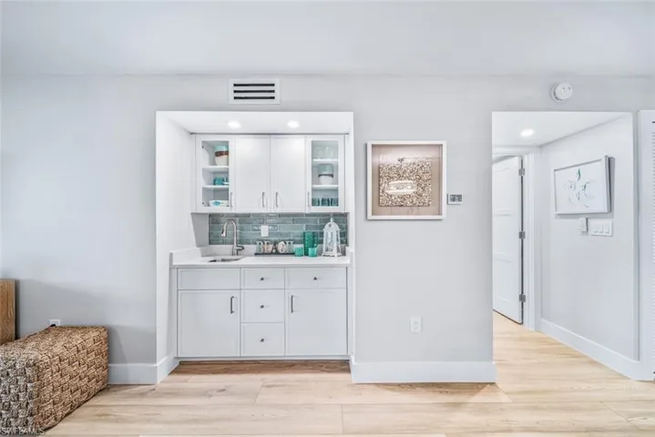 Wet Bar featuring sink, white cabinetry, and tasteful backsplash.