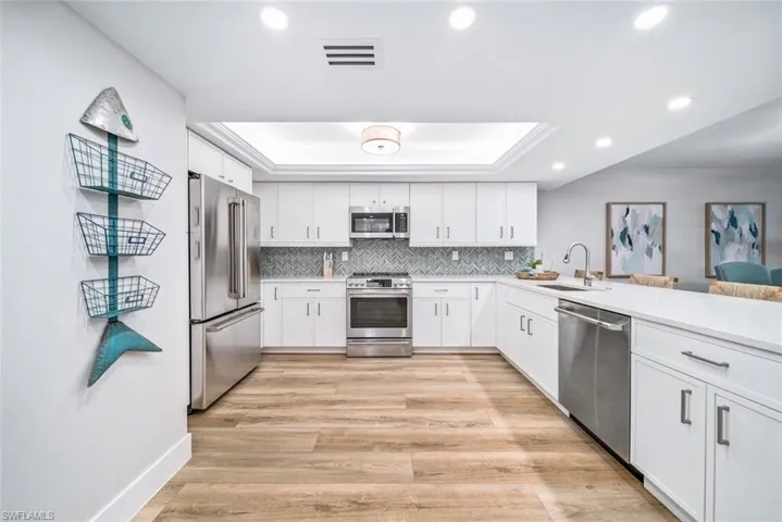 Kitchen with appliances with stainless steel finishes, sink,  and a raised ceiling