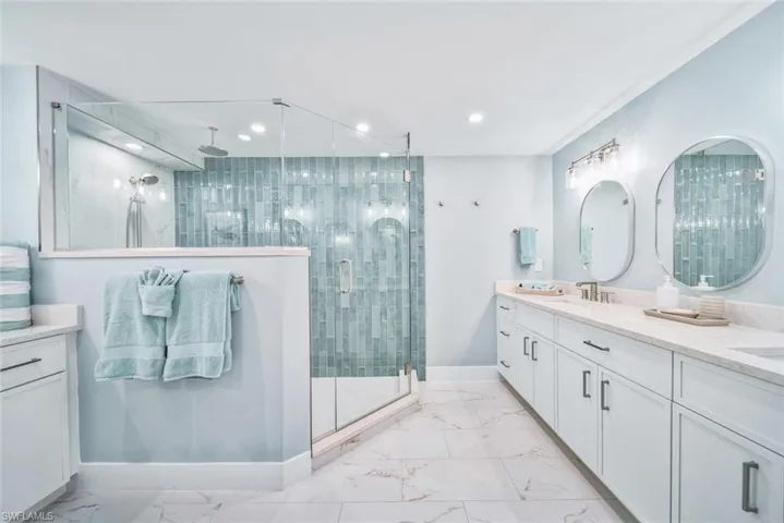 Bathroom with a shower with glass shower door, dual bowl vanity, and tile flooring