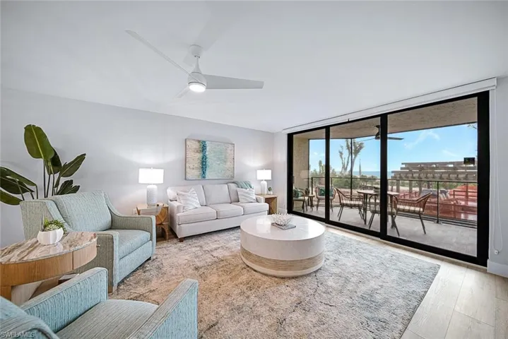 Living room with wood-style flooring, ceiling fan, and a wall of windows