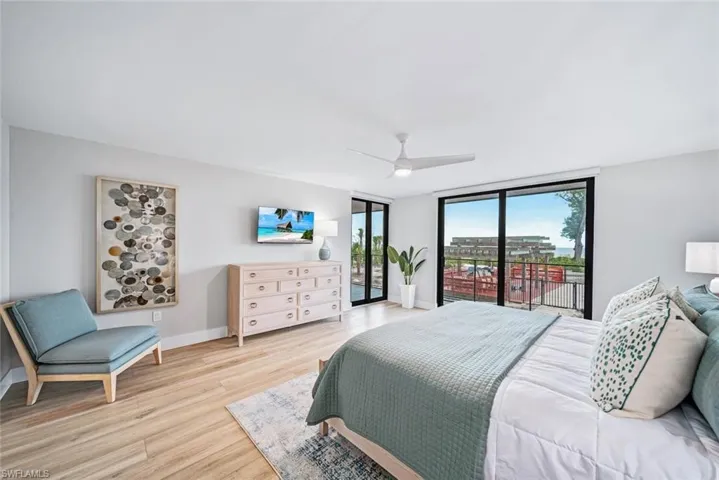 Primary bedroom with access to outside, expansive windows, ceiling fan, and light wood-style flooring