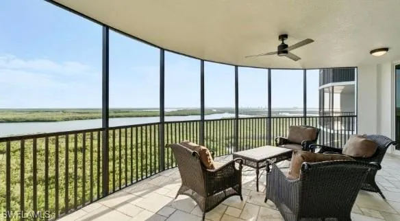 Sunroom / solarium with a water view, a wall of windows, stone tile flooring, and a textured ceiling