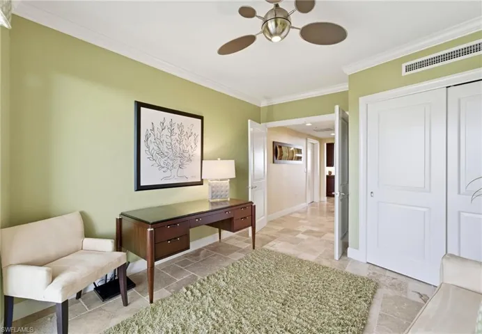 Office with crown molding, a ceiling fan, and stone tile floors