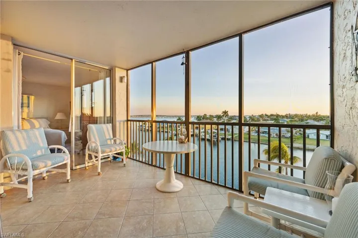 Sunroom / solarium featuring a water view, tile patterned flooring, healthy amount of natural light, and expansive windows